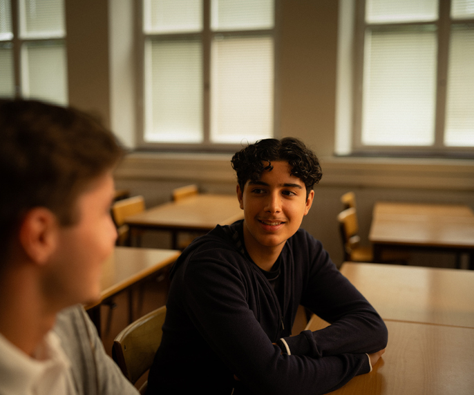 Två elever pratar med varandra i ett klassrum.