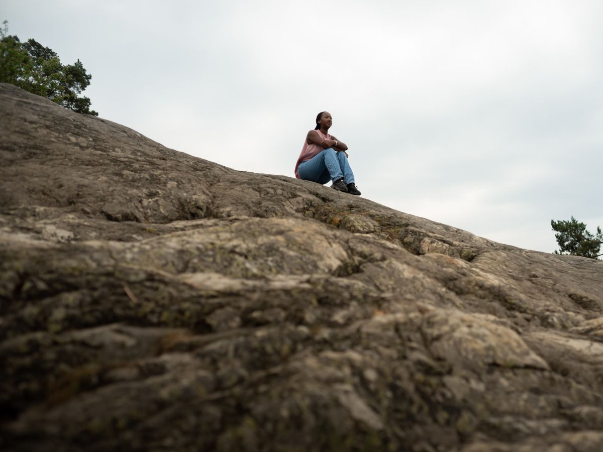 Ung kvinna sitter på klippor