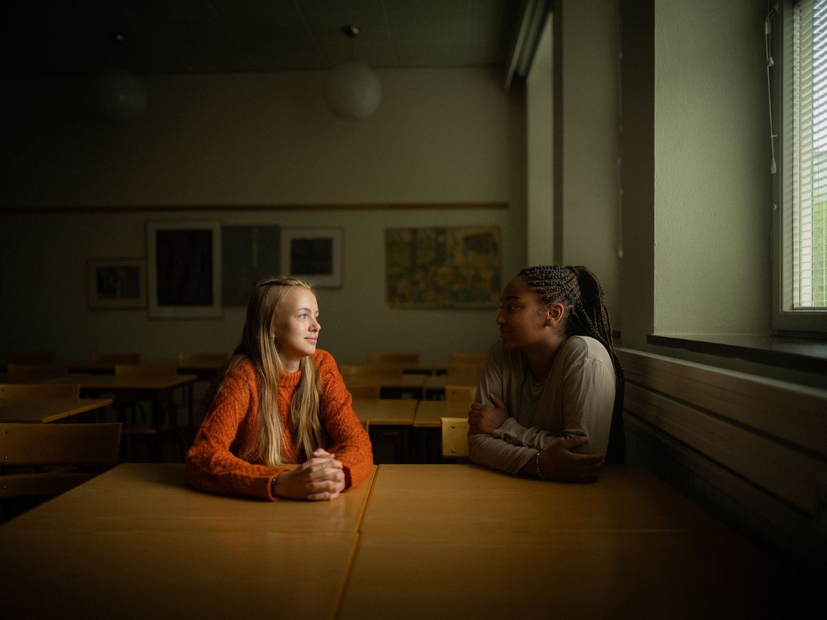 Två unga elever samtalar i ett klassrum.