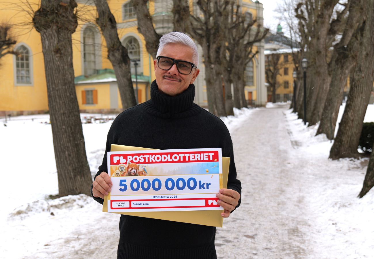 Magnus Skogsberg Tear, ambassadör för Sucide Zero håller upp check på 5000 000 krono. från Postkodlotteriet.