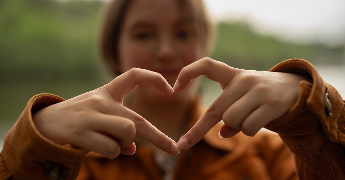 Ung kvinna formar ett hjärta med sina händer.